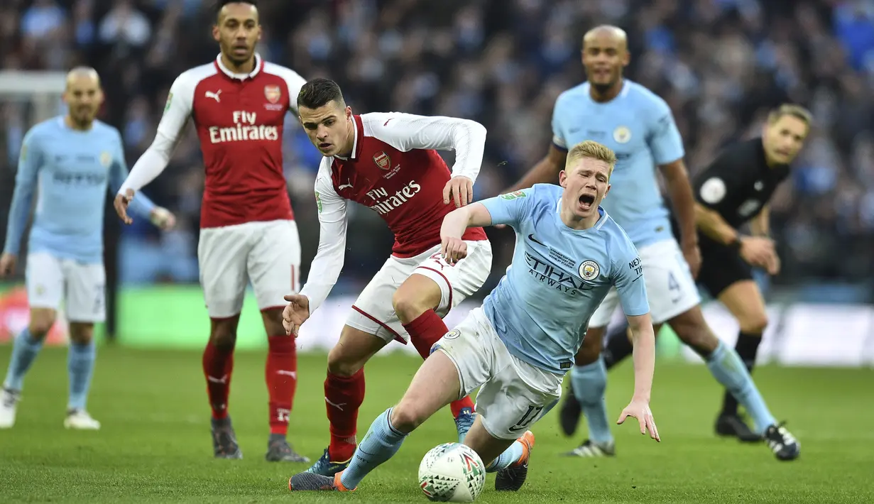 Gelandang Arsenal, Granit Xhaka, menjatuhkan gelandang Manchester City, Kevin De Bruyne, pada final Piala Liga di Stadion Wembley, London, Minggu (25/2/2018). City menang 3-0 atas Arsenal. (AFP/Glyn Kirk)