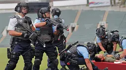Aksi petugas polisi menolong korban saat latihan anti-teror di Hong Kong, Jumat, (25/8). Simulasi serangan anti-teror ini untuk persiapan sebuah konser penyanyi Ariana Grande pada 21 September 2017. (AP Photo / Vincent Yu)