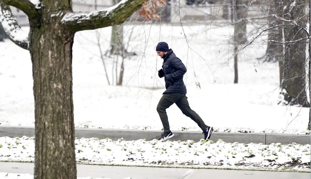 Seorang pria berlari melewati taman bersalju di Nashville, Tennessee, Amerika Serikat, 16 Januari 2022. (AP Photo/Mark Humphrey)