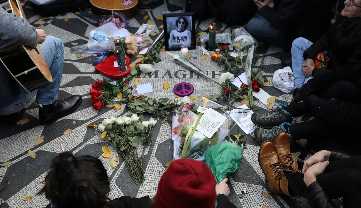 Sebuah foto John Lennon dikelilingi beberapa tangkai bunga mawar yang dibawa para penggemar The Beatles saat memperingati 36 tahun kematian John Lennon di Strawberry Fields, New York, AS (8/12). (Reuters/Mark Kauzlarich)