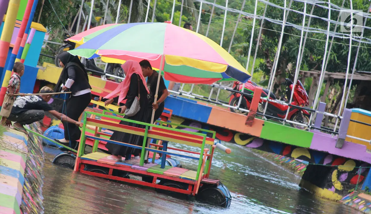 Wisatawan menuruni perahu apung di Wisata Air Toino, Desa Talulobutu, Kecamatan Tapa, Kabupaten Bone Bolango, Gorontalo, Sabtu (30/3). Pengunjung bisa menaiki perahu apung warna-warni sembari menikmati sejuknya alam sekitar. (Liputan6.com/Arfandi Ibrahim)