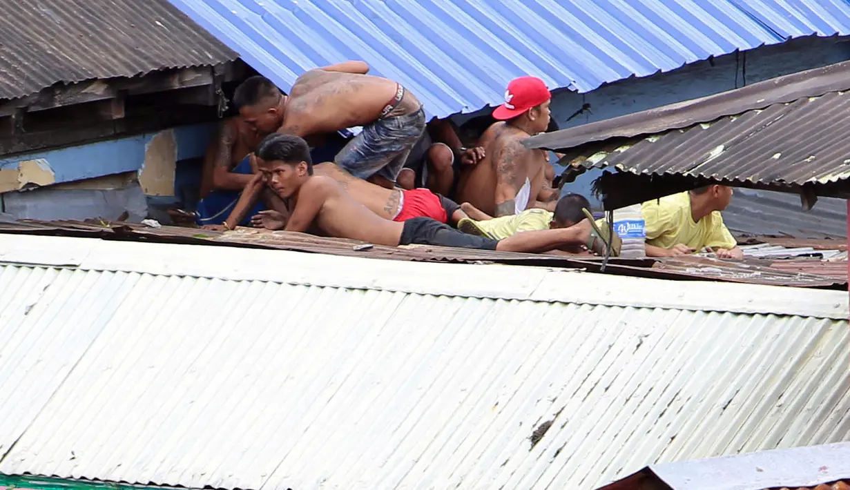 Para narapidana bersembunyi di bawah atap penjara setelah aksi protes dibubarkan petugas polisi di Manila City Jail, Filipina (13/10).  Mereka berunjuk rasa menuntut penggantian kepala penjara. REUTERS/Stringer)
