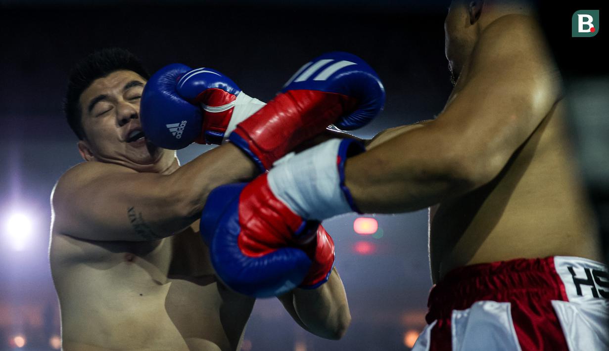 Ekspresi Chef Arnold (kiri) saat terkena pukulan dari konten kreator Codeblue dalam pertarungan tinju Holywings Sports Show (HSS) seri kelima di Indonesia Arena, Kompleks Stadion Utama Gelora Bung Karno, Senayan, pada Minggu (22/04/2024). (Bola.com/Bagaskara Lazuardi)