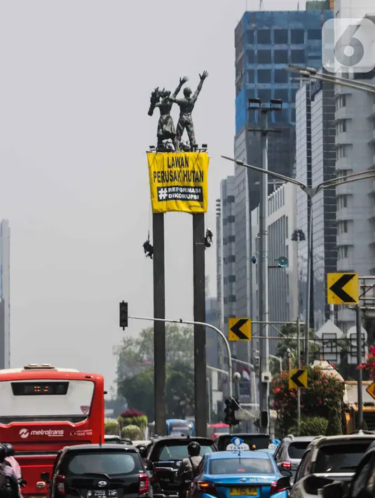 Sejumlah orang membentangkan spanduk di Patung Selamat Datang, Bundaran HI, Jakarta, Rabu (23/10/2019). Aksi ini dilakukan untuk menggalang kepedulian terhadap lingkungan Indonesia. (Liputan6.com/Faizal Fanani)