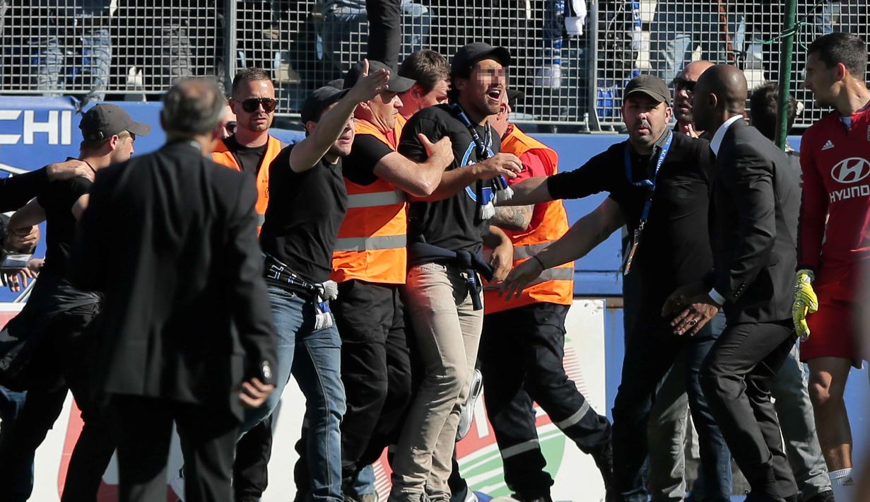 Suporter Bastia diamankan petugas keamanan saat terjadi bentrok dengan pemain Lyon pada laga Ligue 1 Prancis di Armand Cesari stadium, Bastia, (16/4/2017). Laga ini akhirnya dihentikan LFP. (AFP/Pascal Pochard-Casabianca)