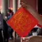 Seorang wanita memamerkan Chunlian berbentuk naga yang ditulis dengan kaligrafi dalam sebuah acara menjelang Tahun Baru Imlek Naga di Kuil Konghucu di Taipei pada tanggal 27 Januari 2024. (Sam Yeh/AFP)