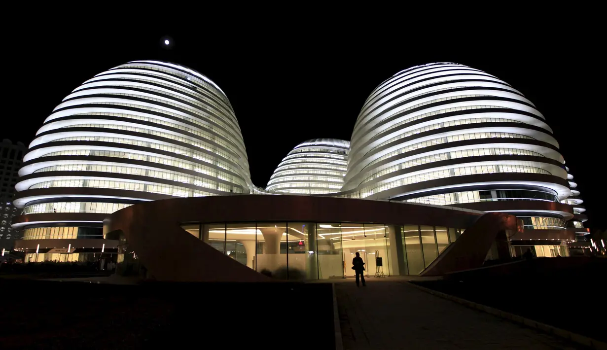 Seorang pengunjung saat berjalan didepan gedung Galaxy Soho yang baru dibuka rancangan arsitek Irak - Inggris Zaha Hadid di Beijing 27 Oktober 2012. (REUTERS / Jason Lee)