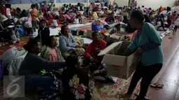 Seorang wanita membagikan makanan untuk berbuka kepada para pengungsi letusan Gunung Sinabung, Medan, Sabtu (4/7/2015). Pengungsi yang muslim tetap menjalankan puasa dengan menu sahur dan berbuka seadanya. (Liputan6.com/JohanTallo)