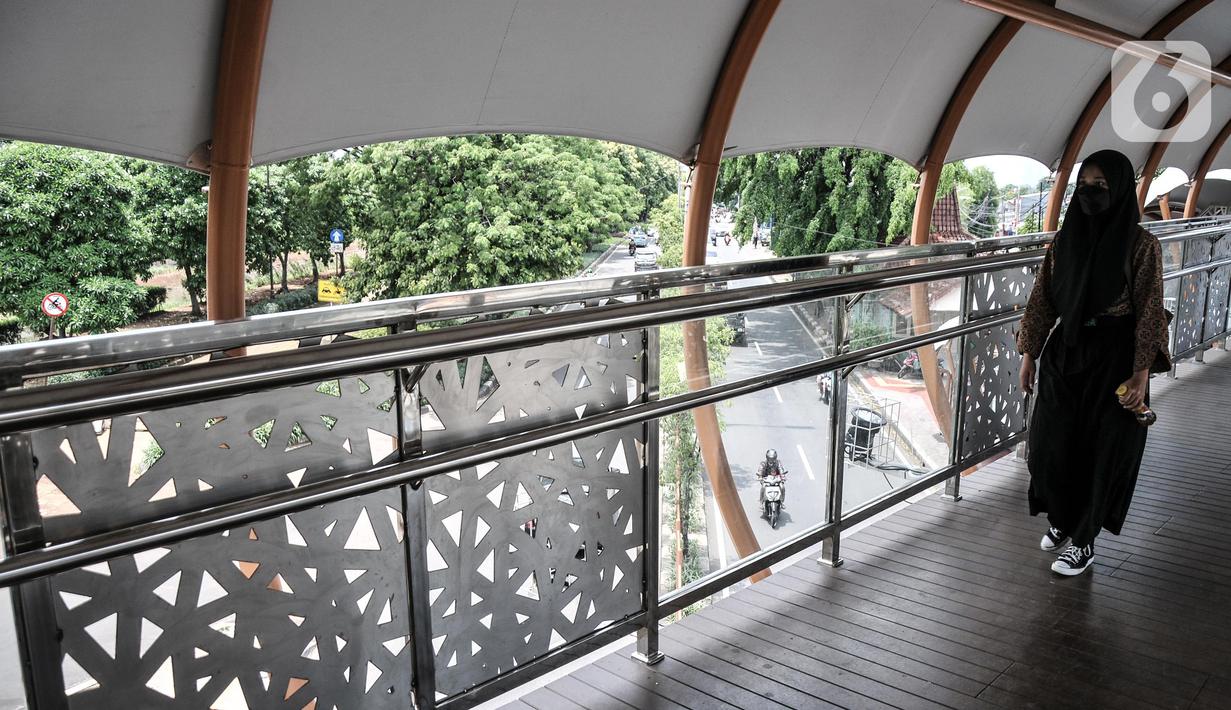 Pejalan kaki menggunakan fasilitas jembatan penyeberangan orang (JPO) di Jalan Kolonel Sugiono, Duren Sawit, Jakarta, Senin (7/2/2022). Tak hanya menonjolkan keindahan arsitekturnya, JPO ini juga ramah bagi penyandang disabilitas karena sudah dilengkapi dengan lift. (merdeka.com/Iqbal S Nugroho)