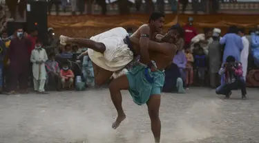 Pegulat bertarung selama turnamen gulat tradisional Sindhi Malakhra di kota pelabuhan Karachi, Pakistan pada Minggu (13/12/2020). Gulat kuno yang dimulai sejak 5.000 tahun lalu ini salah satu olahraga favorit di kalangan pria. (Photo by Asif HASSAN / AFP)