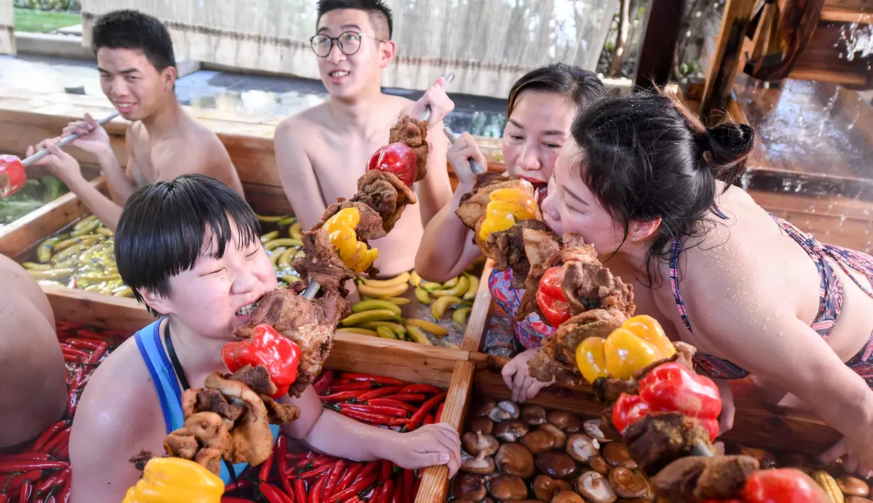 Pengunjung menyantap daging tusuk sambil menikmati berendam di kolam air panas berbentuk hot pot di sebuah hotel di Hangzhou, China, Minggu (27/1). Pemandian air panas itu dirancang untuk mempromosikan gaya hidup sehat menjelang Tahun Baru Imlek (STR/AFP)