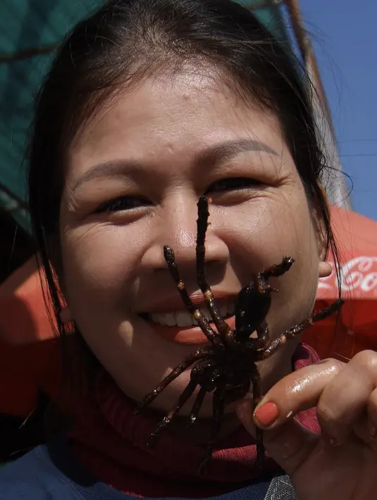 Seorang pedagang Kamboja menunjukkan tarantula goreng yang dijualnya di wilayah Skun, Provinsi Kampong Cham, 4 Desember 2019. Daerah yang kerap dijuluki "Spiderville" tersebut menjadi tempat menarik bagi para turis berburu aping, camilan tradisional dari tarantula ini. (TANG CHHIN Sothy / AFP)