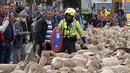 Petugas polisi mengatur rambu lalu lintas saat sekawanan domba melewati pusat kota Madrid, Spanyol, Minggu (23/10/2022). Domba-domba "saba kota" ini bagian dari festival yang menciptakan kembali praktik pastoral memindahkan ternak ke tempat penggembalaan baru. (AP Photo/Paul White)