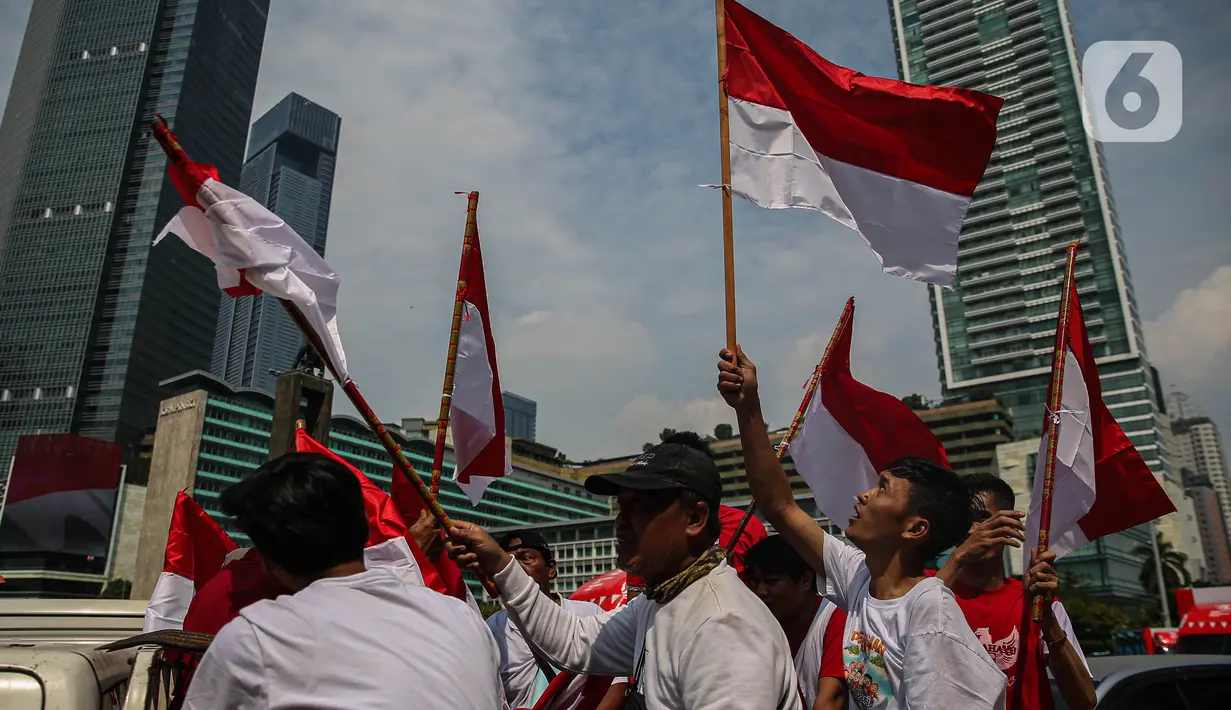 Sejumlah warga yang melintas mengibar-ngibarkan bendera Merah Putih saat melintasi kawasan Bundaran Hotel Indonesia, Jakarta, Sabtu (17/8/2024). (Liputan6.com/Angga Yuniar)