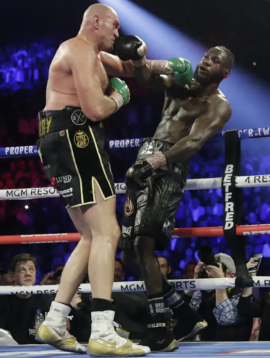 Petinju Inggris Tyson Fury melancarkan pukulan ke arah wajah petinju AS Deontay Wilder pada pertandingan tinju kelas berat WBC di Las Vegas (23/2/2020). Tyson Fury berhasil memenangkan pertarungan di ronde ketujuh. (AP Photo/Isaac Brekken)