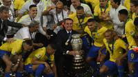 Presiden Brasil, Jair Bolsonaro (pegang trofi), berfoto bersama dengan skuat Selecao setelah menjuarai Copa America 2019 di Stadion Maracana, Rio de Janeiro, Senin (8/7/2019) dini hari WIB. (AFP/Mauro Pimentel)