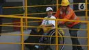 Pekerja PT Kereta Api Indonesia (Persero) membantu salah satu penyandang disabilitas yang mengikuti program Mudik Gratis di Stasiun Pasar Senen, Jakarta, Minggu (7/4/2024). (Liputan6.com/Helmi Fithriansyah)