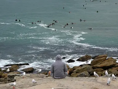 Seorang pria menyaksikan Pantai Maroubra yang dibuka kembali di Sydney (20/4/2020). Pihak berwenang di Sydney membuka kembali tiga pantai untuk aktivitas warga yang ingin berenang ataupun berselancar di tengah pembatasan sosial yang diberlakukan di tengah wabah Covid-19. (AFP/Saeed Khan)