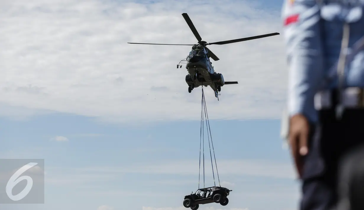 Helikopter Super Puma yang mengangkut kendaraan P-6 ATV saat unjuk kebolehan simulasi penyelamatan sandera dalam rangkaian acara perayaan ulang tahun TNI AU di Halim Perdanakusuma, Minggu (9/4). TNI AU memperingati HUT ke-71. (Liputan6.com/Faizal Fanani)