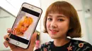 Personel girlband Six Bomb, Kim Da-Young atau Da-In, memperlihatkan foto dirinya sebelum menjalani operasi plastik di sebuah salon kecantikan di Seoul, Korsel, 16 Maret 2017. Da-In menjalani operasi plastik pada bagian atas tubuhnya. (YELIM LEE/AFP)