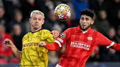 Pemain Borussia Dortmund, Julian Ryerson (kiri) berebut bola dengan pemain PSV, Ricardo Pepi pada laga leg pertama 16 besar Liga Champions 2023/2024 di The Philips Stadium, Eindhoven, Belanda, Rabu (21/02/2024) dini hari WIB. (AFP/John Thys)
