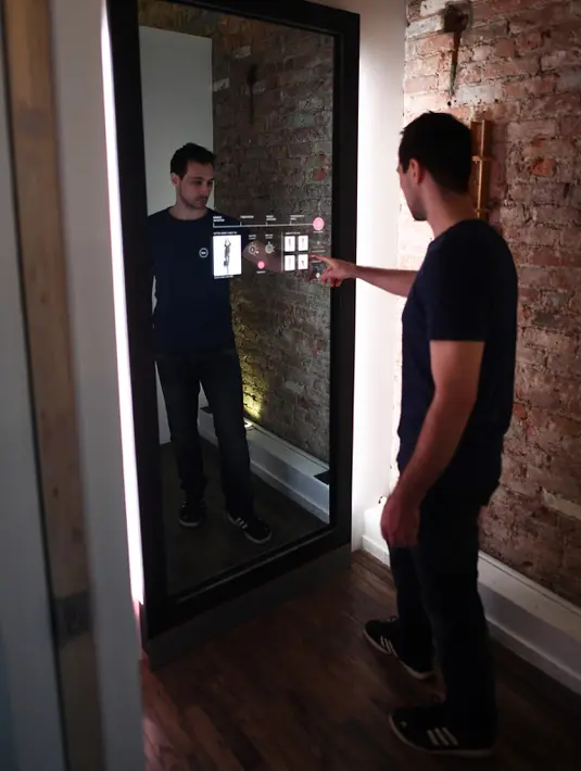 Wesley Bliss menunjukkan cara berinteraksi dengan cermin pintar Oak Fitting Room di sebuah butik, New York, AS (7/2). Cermin ini juga dapat mengukur tubuh sehingga merekomendasikan pakaian yang cocok. (AFP Photo / Jewel Samad)