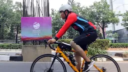 Seorang pesepeda melintas di samping tiang monorel yang dipasangi banner KTT ASEAN di kawasan Jalan Rasuna Said, Jakarta, Minggu (3/9/2023). Pemasangan banner pada 100 tiang monorel tersebut dilakukan guna menyambut penyelenggaraan KTT ASEAN ke-43 yang digelar pada 5-7 September 2023 di Jakarta. (Liputan6.com/Herman Zakharia)