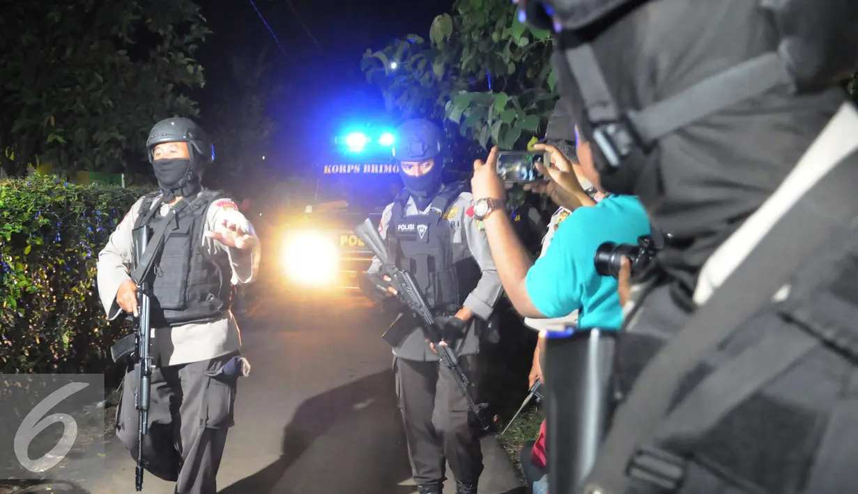 Petugas mengawal ambulan yang berisi mayat terduga teroris di Setu, Tangerang Selatan, Banten, Rabu (21/12). Densus 88 terlibat baku tembak yang akhirnya menewaskan tiga orang terduga teroris. (Liputan6.com/Helmi Afandi)