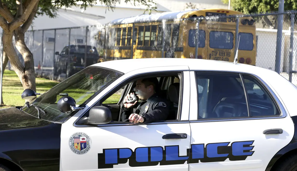 Petugas berjaga di luar Mark Twain Middle School, Los Angeles, Selasa (15/12). Seluruh sekolah di Los Angeles, ditutup selama satu hari pada Selasa (15/12), karena adanya ancaman teror bom. (REUTERS/Jonathan Alcorn)