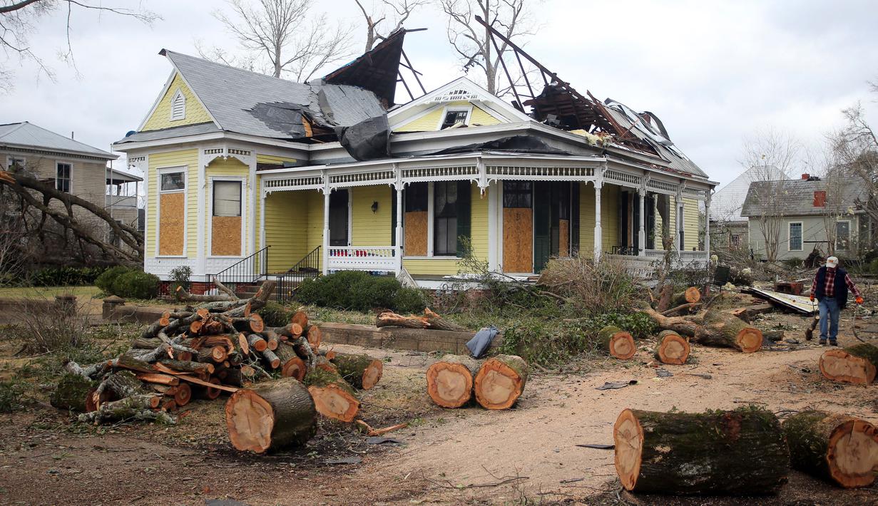 Sisa-sisa pohon tumbang tergeletak di depan rumah yang rusak setelah tornado di Selma, Alabama, Amerika Serikat, 13 Januari 2023. Kantor NWS di Birmingham memperingatkan bahwa "darurat tornado" telah dikeluarkan untuk Autauga County. (AP Photo/Stew Milne)