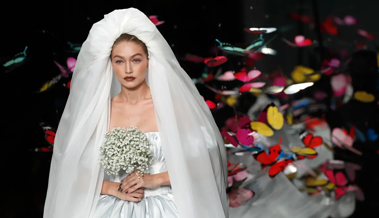 Supermodel Gigi Hadid berjalan di runway mengenakan gaun rumah mode Moschino untuk koleksi SS19 selama gelaran fashion week di Milan, Italia, Kamis (20/9). Gigi Hadid mencuri perhatian publik dengan tampil bak seorang pengantin. (AP/Antonio Calanni)