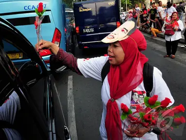 Relawan Jokwi-JK saat membagikan bunga kepada pengendara yang melintas di Bundaran HI, Jakarta, (17/10/14). (Liputan6.com/Johan Tallo)