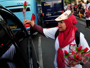 Relawan Jokwi-JK saat membagikan bunga kepada pengendara yang melintas di Bundaran HI, Jakarta, (17/10/14). (Liputan6.com/Johan Tallo)