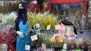 Seorang pedagang menata bunga pada hari pembukaan pasar bunga di Hong Kong (16/1/2023). Tahun Baru Imlek tahun ini jatuh pada tanggal 22 Januari 2023. (AFP/Peter Parks)