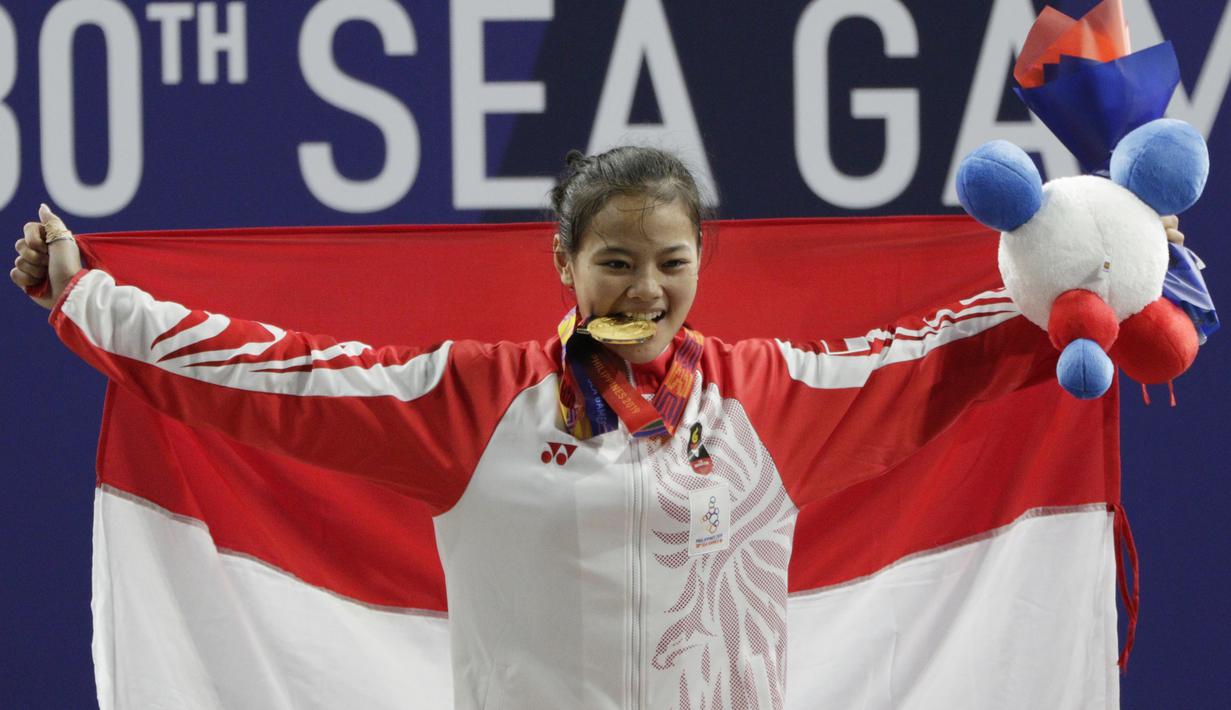 Lifter Windy Aisyah mengibarkan bendera usai mendapatkan medali emas SEA Games 2019 cabang angkat besi nomor 49 kg di Stadion Rizal Memorial, Manila, Minggu (1/12). Dirinya meraih emas dengan total angkatan 104 kg. (Bola.com/M Iqbal Ichsan)
