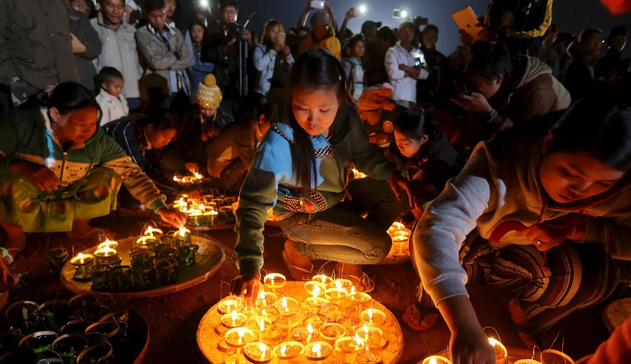 Sejumlah warga menyalakan lilin sebelum melepaskan lampion buatan tradisional ke langit selama festival tahunan Tazaungdaing di Taunggyi, Myanmar (19/11). (REUTERS/Soe Zeya Tun)