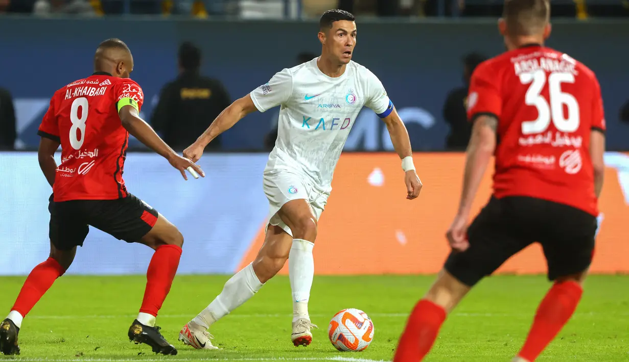 Pemain Al Nassr, Cristiano Ronaldo (tengah), mengontrol bola dibayangi dua pemain Al Riyadh dalam laga pekan ke-16 Saudi Pro League 2023/2024 yang digelar di Al Awwal Park, Sabtu (9/12/2023) dini hari WIB. (AFP/Fayez Nureldine)