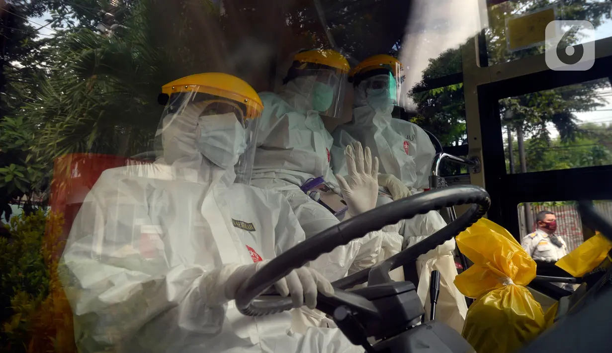 Petugas Dishub memakai baju APD akan menjemput korban yang diduga terjangkit Covid-19 menggunakan bus sekolah di Puskesmas Kebayuran Lama, Jakarta, Senin (6/7/2020). Bus sekolah tersebut selama liburan dibantukan untuk mengangkut pasien Covid-19 ke Wisma Atlet Kemayoran. (merdeka.com/Dwi Narwoko)