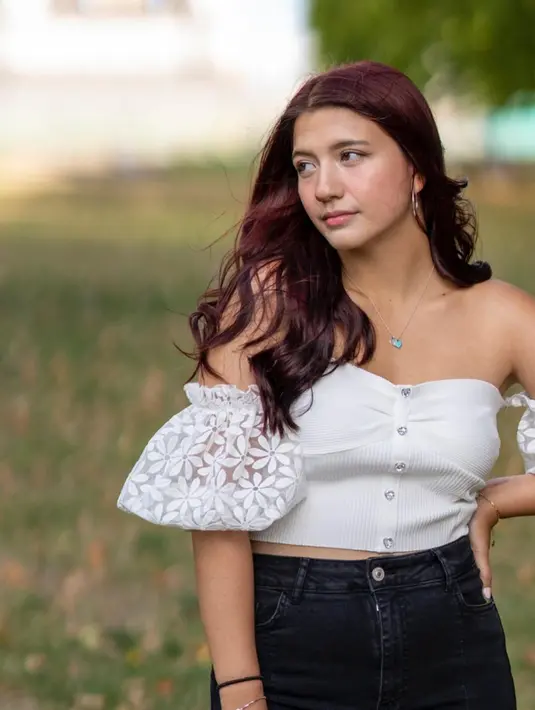 Cassandra Lee saat berpose dengan gaya yang muka menoleh ke samping. Dia tampil mengenakan blus Sabrina berwarna putih yang dipadukan dengan celana jeans biru.  (Instagram/cassandrasle)