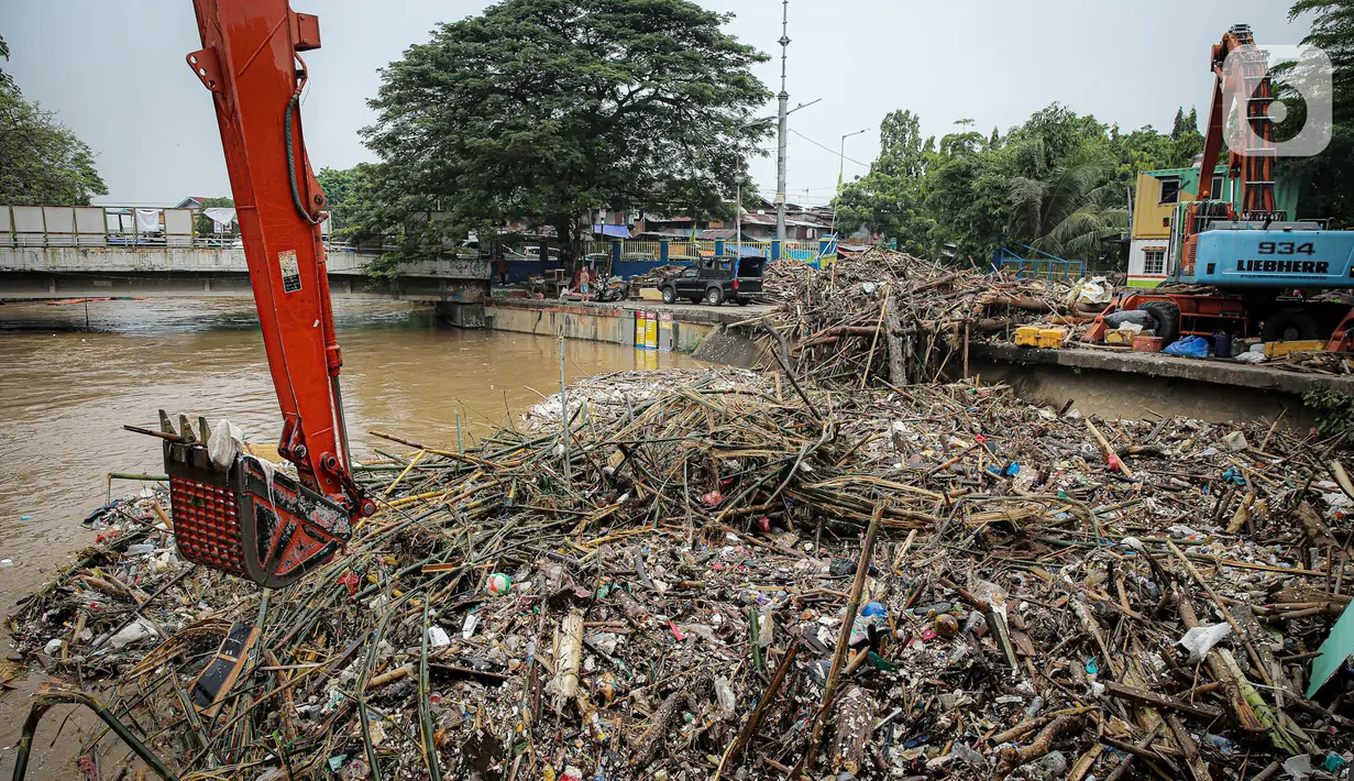 Petugas Dinas Kebersihan DKI Jakarta menggunakan alat berat untuk membersihkan sampah di Pintu Air Manggarai, Jakarta, Senin (10/10/2022). Hujan lebat yang mengguyur wilayah Bogor dan sekitarnya menyebabkan debit air Sungai Ciliwung meningkat dan menghanyutkan sampah ke Pintu Air Manggarai. (Liputan6.com/Faizal Fanani)