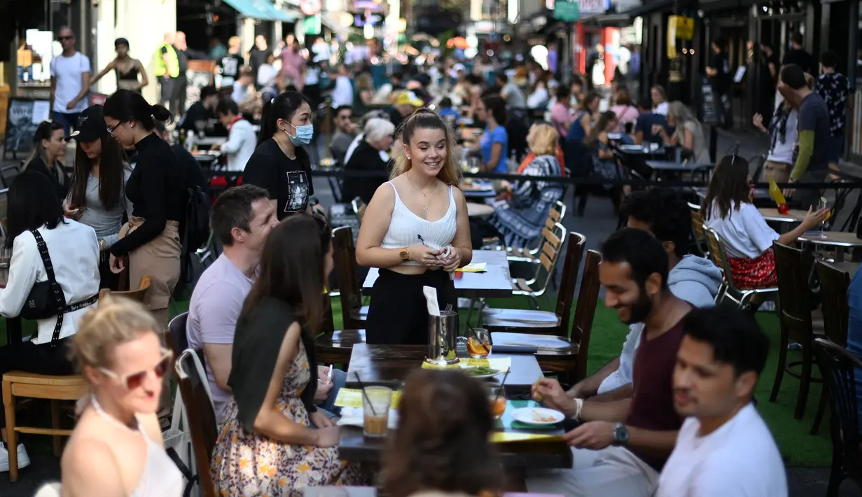 Pramusaji menerima pesanan pelanggan di meja di luar restoran di Soho, London, saat pemerintah Inggris mempertimbangkan pembatasan baru pada Minggu (20/9/2020). Inggris kemungkinan akan kembali memberlakukan tindakan lockdown akibat lonjakan tajam infeksi corona COVID-19. (DANIEL LEAL-OLIVAS/AFP)