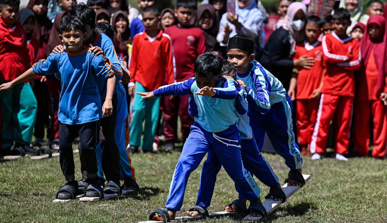 Siswa mengikuti permainan tradisional bakiak pada Festival Permainan Tradisional Anak di Desa Wisata Lubok Sukon, Kecamatan Ingin Jaya, Aceh Besar, Aceh, Sabtu (25/7/2026). (AFP/ Chaideer Mahyuddin)