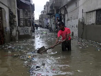 Seorang pria membersihkan jalan yang banjir setelah hujan deras, di Karachi, Pakistan, Selasa (30/7/2019). Departemen Meteorologi Pakistan mengatakan bahwa hujan memasuki provinsi Sindh dari Rajasthan India dan memperkirakan hujan akan turun tiga hari lagi. (AP Photo/Fareed Khan)