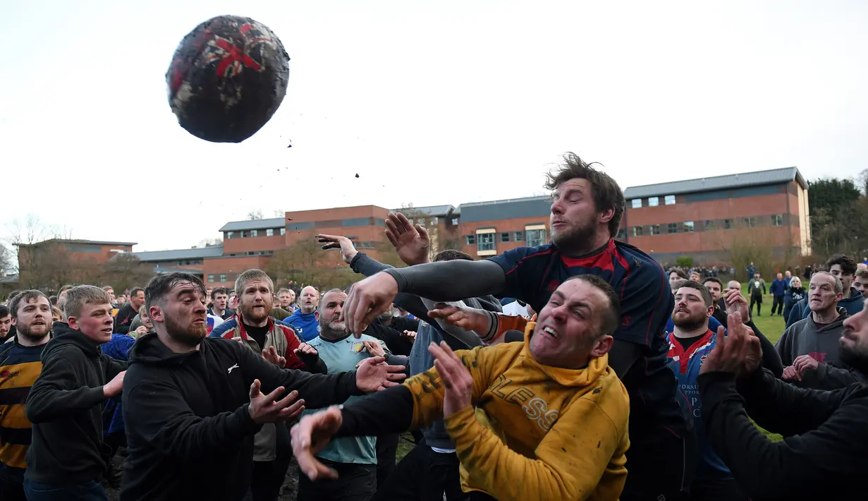 Para peserta berebut bola saat mengikuti Royal Shrovetide Football Match di Ashbourne, Derbyshire, Inggris, Selasa (5/3). Gawang dalam pertandingan ini berada di utara dan selatan Kota Ashbourne. (Oli Scarff/AFP)