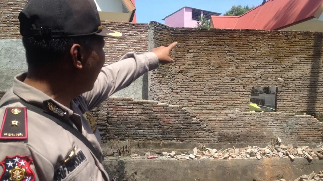 Kapolsek Tamalate, Kompol A. Arifuddin tampak menunjuk bagian tembokpembatas yang runtuh dan menimpa dua bocah bersaudara di Makassar hingga tewas (Liputan6.com/ Eka Hakim)