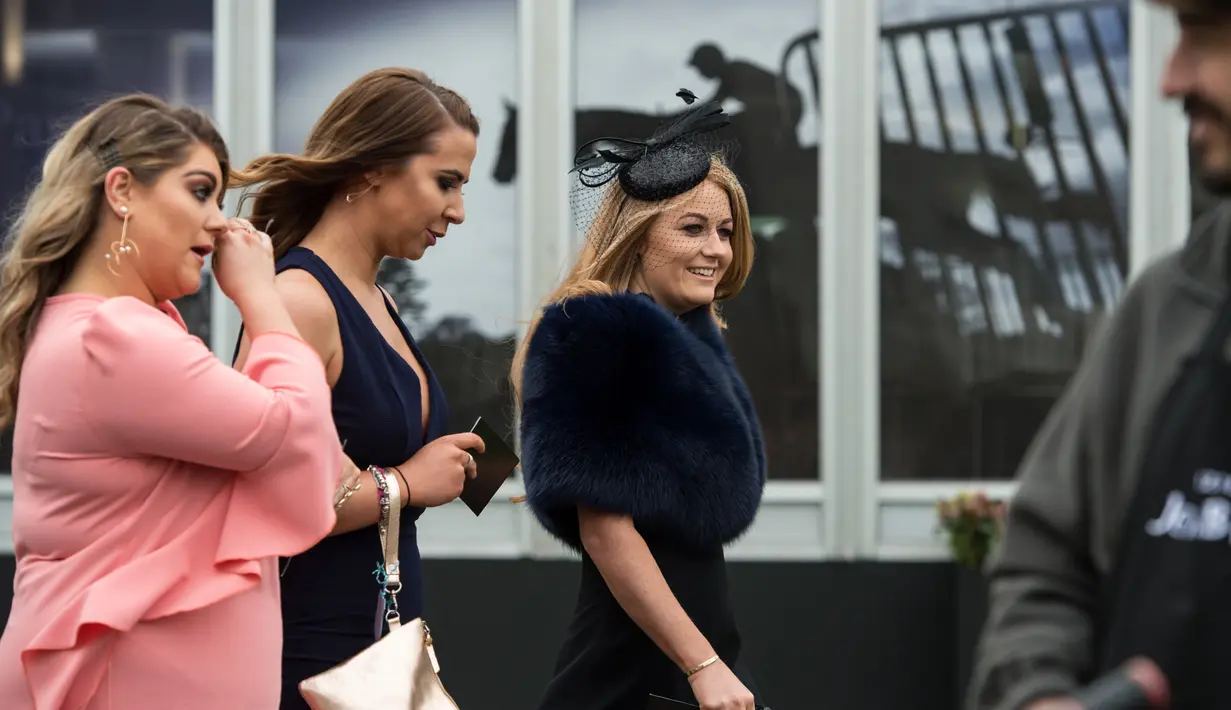 Sejumlah racegoers berdandanan seksi dan modis saat menghadiri Festival Grand National di arena Aintree, Liverpool, Inggris, Jumat (7/4). Kehadiran racegoers memberikan nuansa tersendiri di kompetisi pacuan kuda terbesar tersebut. (AFP Photo / Oli Scarff)