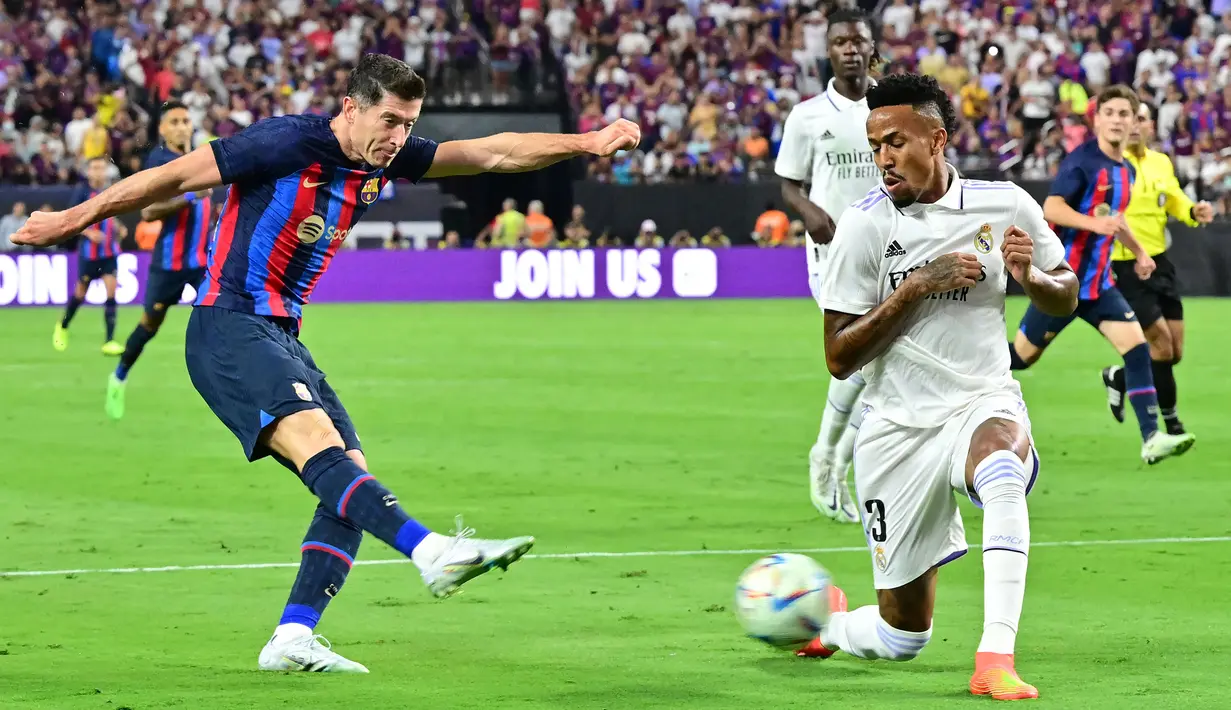 Pemain Barcelona, Robert Lewandowski (kiri) berusaha menembakkan bola melewati pemain Real Madrid, Eder Militao saat pertandingan persahabatan antara Real Madrid melawan Barcelona di Stadion Allegiant, Las Vegas, Amerika Serikat, Minggu (24/07/2022) pagi WIB. (AFP/Frederic J. Brown)