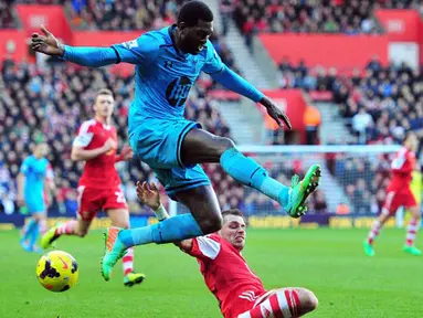 Striker Tottenham Hotspur Emmanuel Adebayor (kiri) menghindari tekel gelandang Southampton Morgan Schneiderlin (kanan) pada pertandingan sepak bola Liga Inggris antara Southampton vs Tottenham Hotspur di Stadion St Mary, Southampton (22/12/13). (AFP/Glyn 
