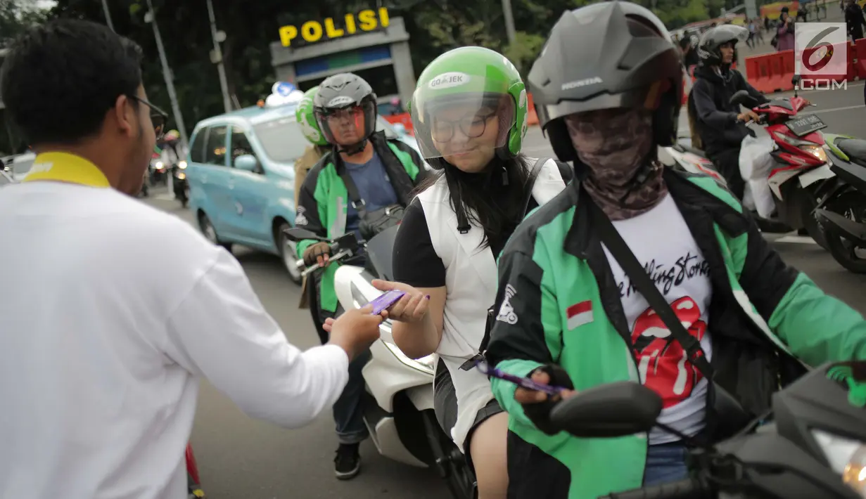 Relawan Millennial Jokowi-Amin membagikan coklat kepada pengendara roda dua dan empat di kawasan Patung Kuda, Jakarta, Kamis (18/4). Kegiatan tersebut sebagai bentuk terima kasih kepada seluruh anak bangsa yang telah ikut memberikan suaranya di TPS. (Liputan6.com/Faizal Fanani)