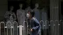 Seorang perempuan dengan masker berjalan di dekat toko ritel yang menjual piyama yang dikunci sebagai bagian dari pengendalian COVID-19 di Beijing, Selasa (14/6/2022). Pihak berwenang memerintahkan pengujian massal tiga hari untuk penduduknya di distrik Chaoyang menyusul terdeteksinya ratusan kasus virus corona COVID-19 terkait dengan klaster bar 24 jam. (AP Photo/Andy Wong)